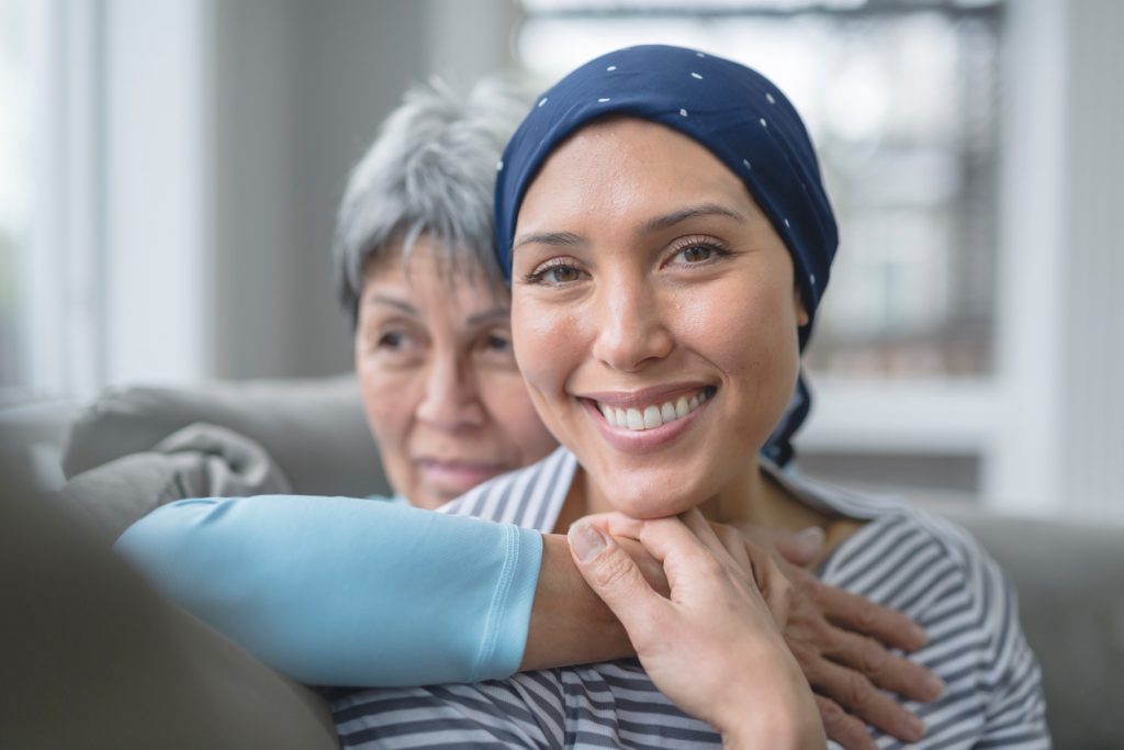 A woman wearing a headscarf sits on the couch with her mother holding her