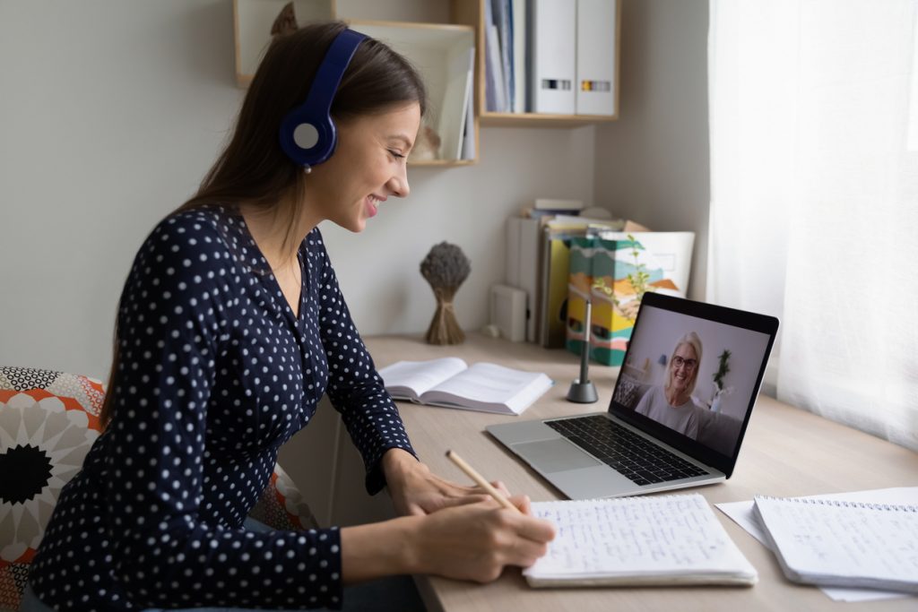 Woman sitting at her desk taking notes while, on a call with a healthcare professional